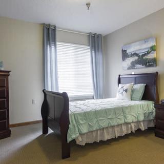 A cozy bedroom with a single bed, a dresser, and calming decor.