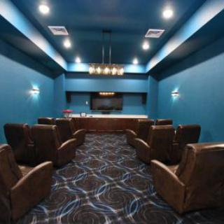 A modern home theater with leather seating and blue walls.