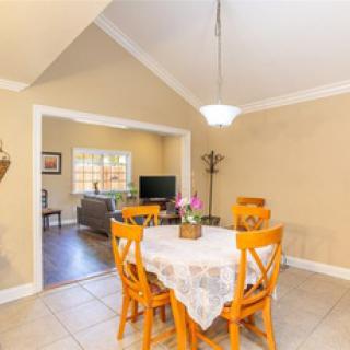 A cozy dining area with a table and chairs, featuring an open layout leading to a living room.