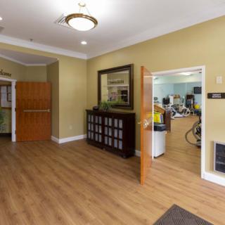 A welcoming lobby area with wood flooring, a mirror on the wall, and an open door leading to another room.