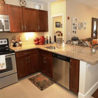 A modern kitchen interior featuring stainless steel appliances and wood cabinets.