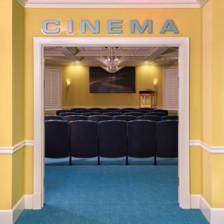 A small cinema room with rows of seats and a projector screen.