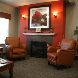 A cozy living room with a fireplace, two leather armchairs, and warm lighting.