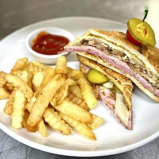 A delicious sandwich served with crinkle cut fries and a side of sauce.
