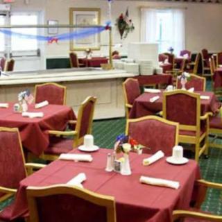 A neatly arranged dining area with red tablecloths and wooden chairs.
