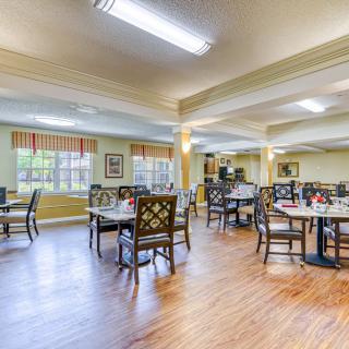 A spacious dining area with neatly arranged tables and chairs, featuring large windows that allow ample natural light.