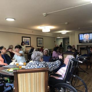 A group of elderly individuals in a nursing home watching television together.