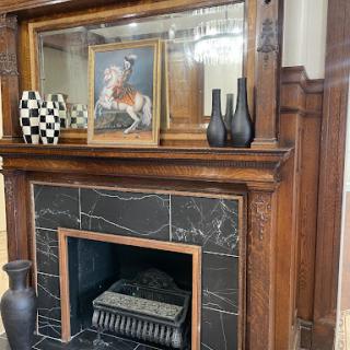A beautifully designed fireplace with wooden detailing, featuring a framed artwork and decorative vases.