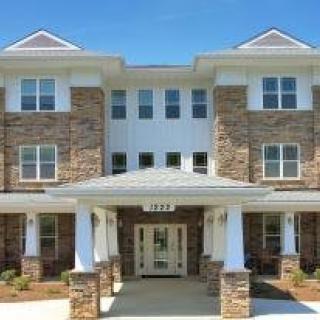 A three-story residential building with a brick facade and a welcoming entrance.