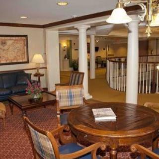 A cozy living room interior with a round wooden table, chairs, couches, and decorative columns.