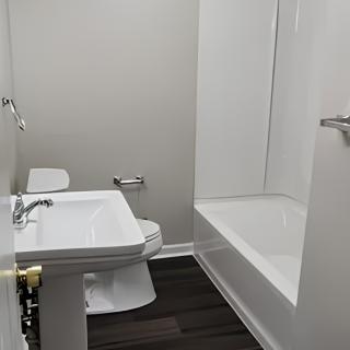 A modern bathroom with a sink, toilet, and bathtub.