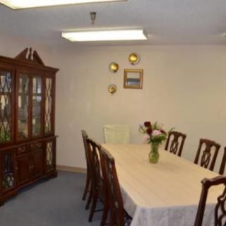 A traditional dining room with a large table and chairs, featuring a china cabinet and floral centerpiece.