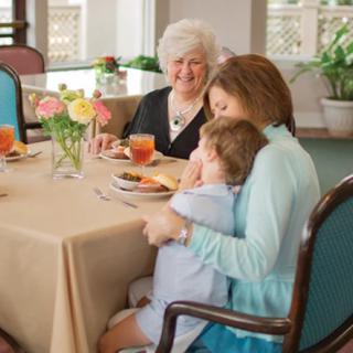 A family enjoying a meal together, with a child hugging an adult at the table.