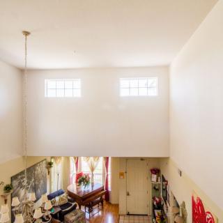 A spacious living area with high ceilings and ample natural light from upper windows.
