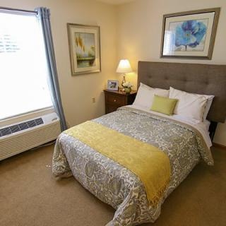 A cozy bedroom with a neatly made bed, decorative pillows, and artwork on the walls.