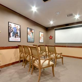 A small conference room with rows of chairs facing a projector screen.