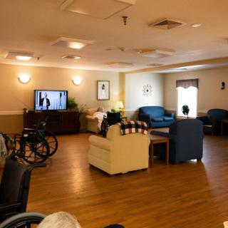 A cozy living room with a television, seating area, and a wheelchair in the corner.