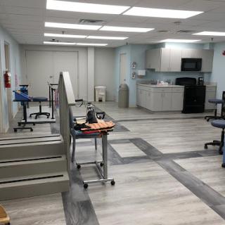 A spacious and modern medical rehabilitation facility featuring workstations and therapy areas.