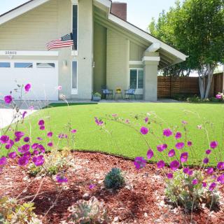 A suburban house with a well-maintained lawn and colorful garden in the foreground.