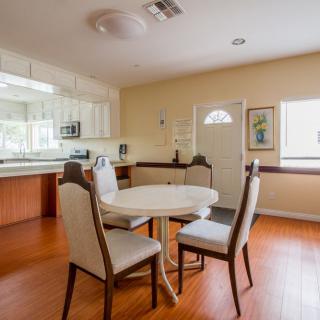 A cozy dining area with a round table and four chairs, adjacent to a modern kitchen.