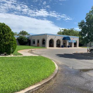 A commercial building surrounded by lush green grass and under a clear blue sky.