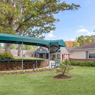 A residential building with a green awning over the entrance, surrounded by trees and well-maintained landscaping.