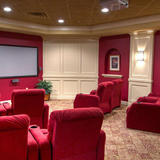A luxurious home theater with red seats and a large projection screen.