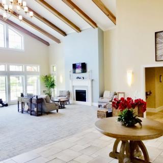 A spacious and elegantly designed living room featuring high ceilings with wooden beams, abundant natural light, and a modern fireplace.