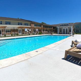 A sunny day at a residential outdoor swimming pool with lounge chairs.