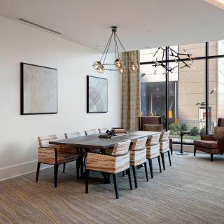 A modern dining room with a large table, wooden chairs, and stylish lighting fixtures.