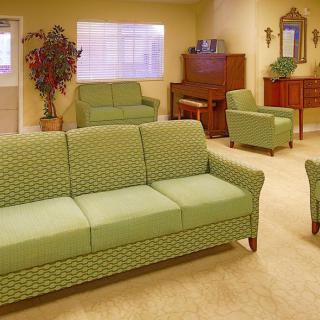 A cozy living room with green sofas and a piano.