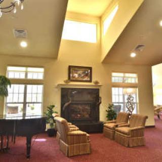 A spacious living room with comfortable seating, a piano, and a fireplace.