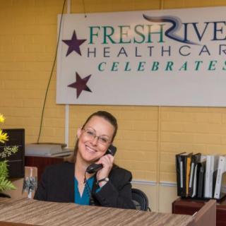 A receptionist talking on the phone in a healthcare office setting.
