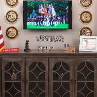 A military-themed display featuring a television showing a patriotic scene, surrounded by medals and awards.