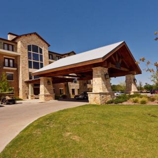 A scenic view of a hotel entrance with stone architecture and landscaped surroundings.