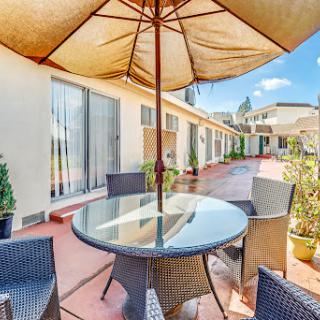 A serene outdoor patio set up with a glass table, stylish chairs, and a protective umbrella.