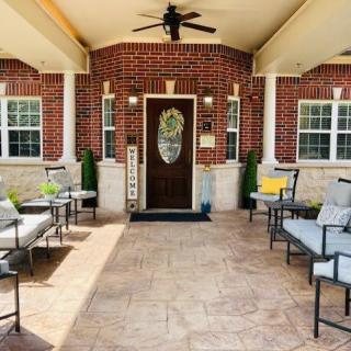 A welcoming porch with comfortable seating and a ceiling fan, framed by brick walls and columns.