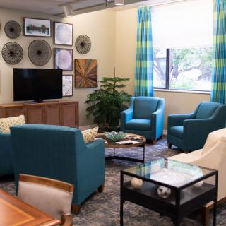 A cozy living room featuring blue armchairs, a television, and stylish wall decor.