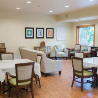 A bright and spacious dining area with tables, chairs, and sofas, adorned with artwork on the walls.