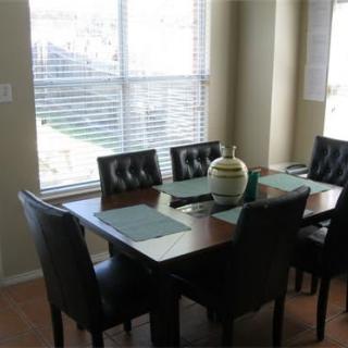 A dining room with a table set and chairs near a large window.