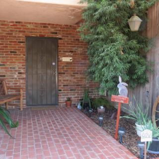 A cozy porch with a brick wall, featuring potted plants and a wooden bench.
