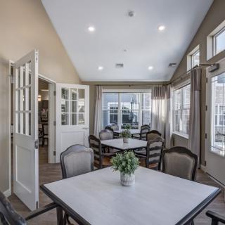 A well-lit dining area with multiple tables and chairs arranged near large windows.