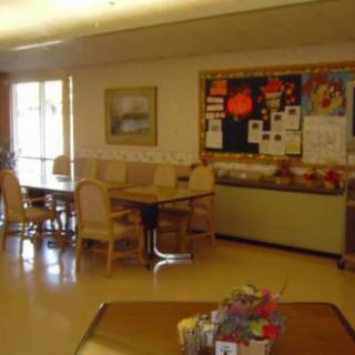 A room with tables, chairs, and a bulletin board decorated with various items.