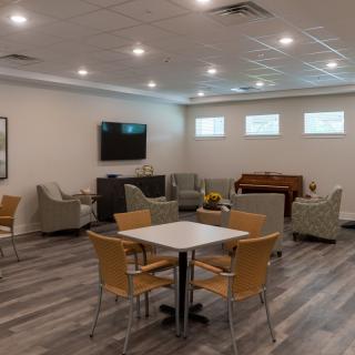 A modern lounge area with comfortable seating, a television, and a piano.