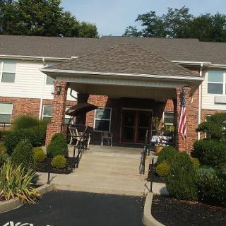 Front entrance of a residential building with landscaping and an American flag.