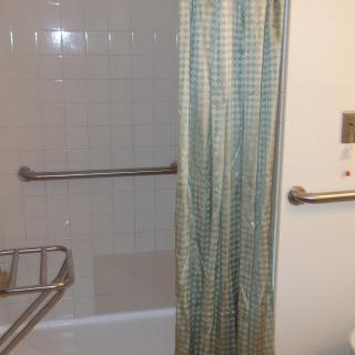 A bathroom featuring a shower with a patterned curtain, tiled walls, and metal fixtures.