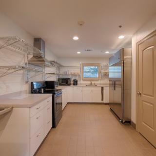 A modern kitchen featuring minimalist design with white cabinetry and stainless steel appliances.