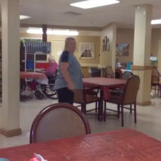 A view of a casual dining area with tables and chairs, where some people are seated in the background.