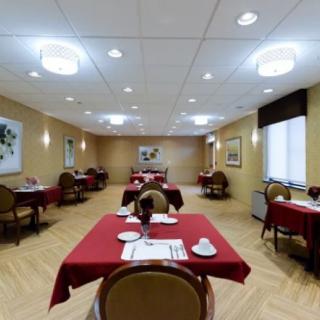 An empty dining room with neatly arranged tables covered in red tablecloths.