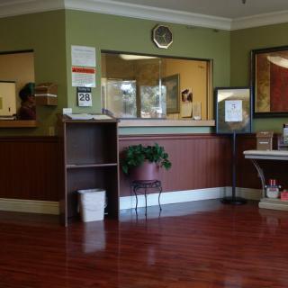 A reception area with a desk, clock, and plant.